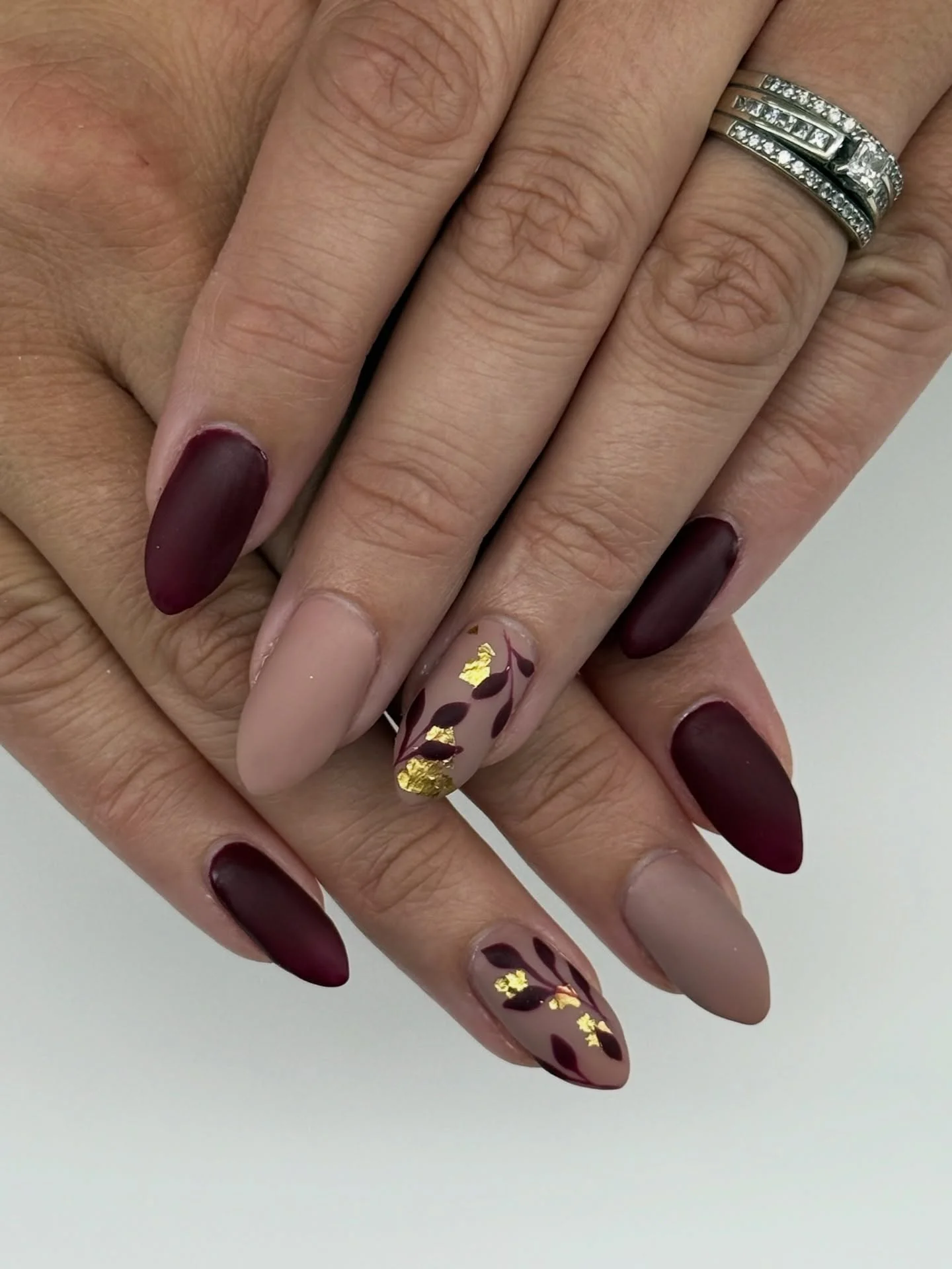 fall accent nail designs 2026 Velvety Burgundy With Gold Foil Leaf Accents