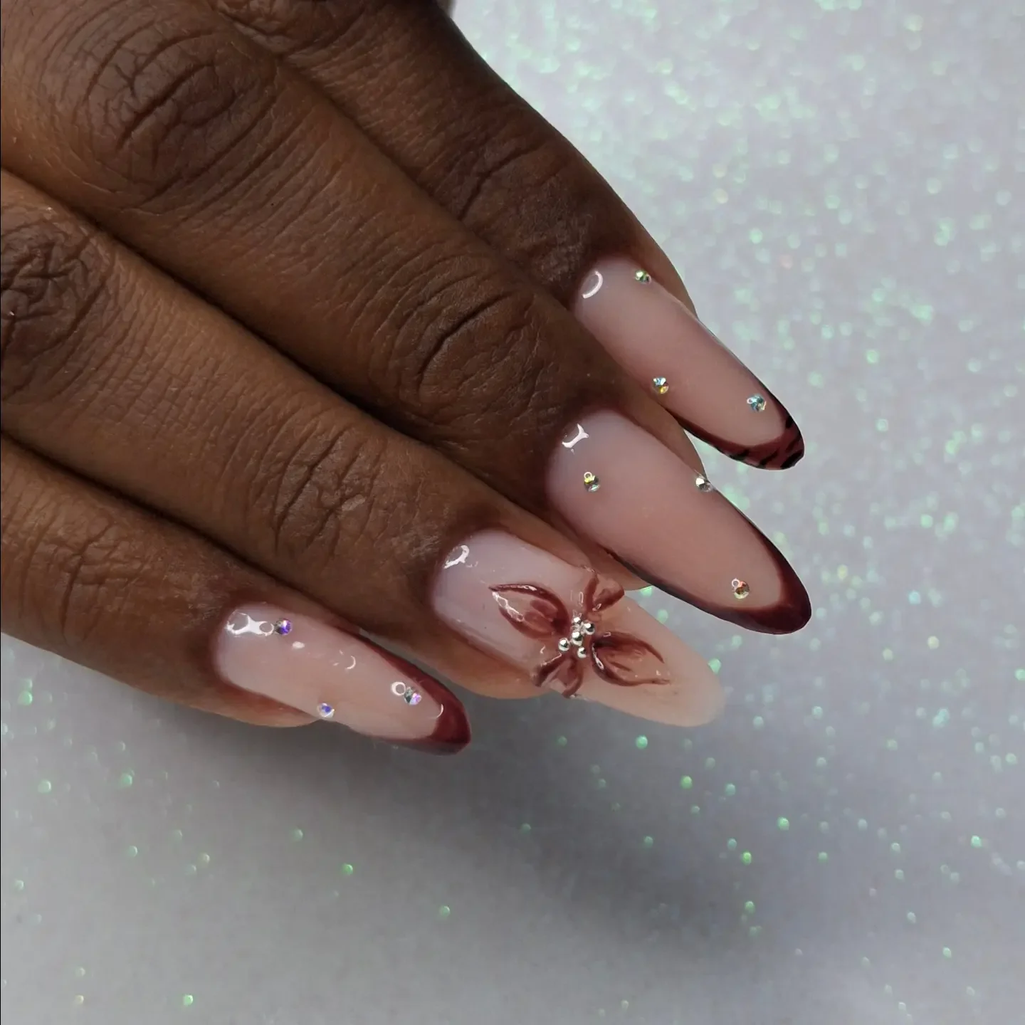 fall nails for dark skin 2026 Glossy Chocolate Floral Nails With Soft Rhinestone Sparkle
